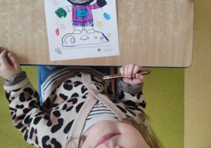 Dziewczynka koloruje pracę plastyczną: ,,Ja w kosmosie".