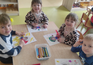 Dzieci kolorują przy stoliku pracę plastyczną: ,,Lot w kosmos".