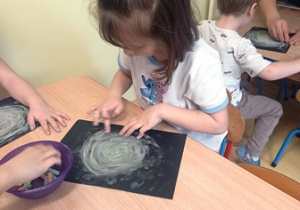 Emilka rozciera kredę na kartce