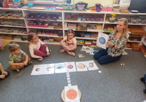 Dzieci siedzą na dywanie i poznają planety Układu Słonecznego