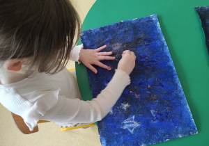 Dziewczynka rysuje gwiazdozbiory na sensorycznym tle.