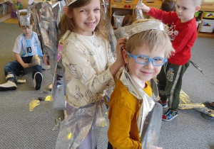 Dziewczynka pomaga chłopcu w zawiązaniu folii aluminiowej.