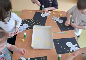 Dzieci przy stoliku w czasie wykonywania pracy plastycznej pracy "Astronauta w galaktyce"
