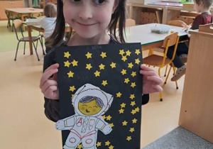 Dziewczynka prezentuje pracę plastyczną pt. "Astronauta w galaktyce"