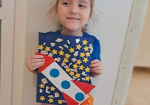 Dziewczynka prezentuje pracę plastyczną pt. "Podróż w kosmos"