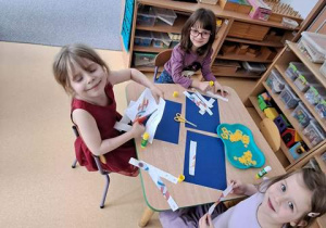 Dziewczynki przy stoliku podczas wycinania elementów rakiety