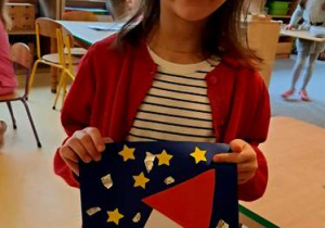 Jagoda prezentuje wykonaną przez siebie pracę plastyczną przedstawiającą rakietę kosmiczną