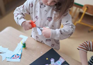 Wiktoria podczas działań plastycznych wycina gwiazdkę