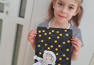 Dziewczynka prezentuje wykonaną przez siebie pracę plastyczną pt. "Astronauta w galaktyce"