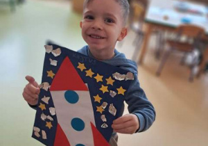 Chłopiec prezentuje pracę plastyczną pt. "Podróż w kosmos"