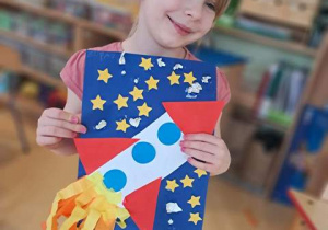 Dziewczynka prezentuje pracę plastyczną pt. "Podróż w kosmos"