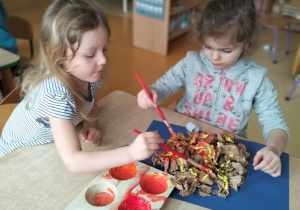 Dziewczynki malują farbami słońce ze zgniecionego papieru