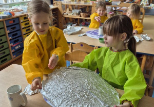 Dziewczynki owijają koło folia aluminiową