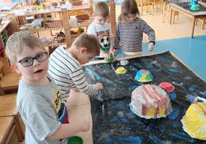 Dzieci posypują makietę "Układ słoneczny" brokatem