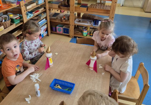 Dzieci podczas przyklejania elementów rakiety do plastikowej butelki