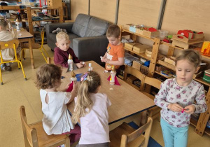 Dzieci podczas przyklejania elementów rakiety do plastikowej butelki