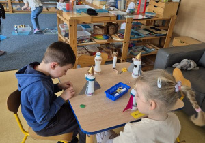 Dzieci podczas przyklejania elementów rakiety do plastikowej butelki