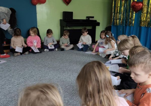 Dzieci siedzą na dywanie i oglądają książeczki