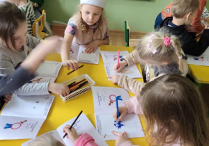 Dzieci wykonują rysunki w książeczkach