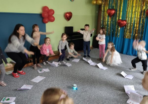 Dzieci oraz prowadząca zajęcia wykonują przysiady