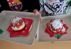 Zdjęcie przedstawia tace ze zrobionymi przez dzieci pączkami w czasie zabawy plastycznej