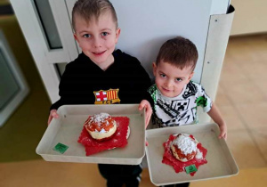 Chłopcy prezentują wykonane przez siebie podczas zabawy plastycznej przestrzenne konstrukcje pączka z papieru