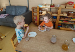 Chłopcy siedzą przy stoliku i jedzą pączki