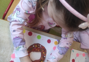 Dziewczynka lukruje pączki.