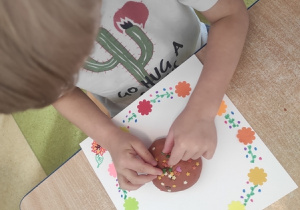 Chłopiec dekoruje swojego pączka kolorową posypką.