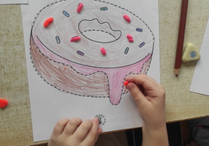 Dziecko wykleja kontury pączka ciastoliną.