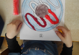 Chłopiec wykleja kształt pączka modeliną.