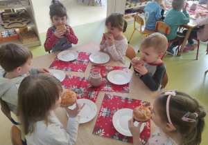 Dzieci delektują się pączkami.