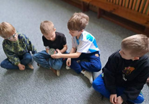 Dzieci siedzą na dywanie i oglądają puszkę mleka kokosowego