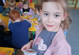 Dziewczynka trzyma w dłoniach zdrowy deser przygotowany w czasie warsztatów