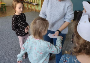 Dziewczynka losuje karteczkę z ręki prowadzącej zajęcia