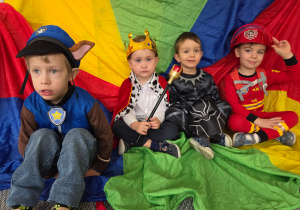 Chłopcy w strojach karnawałowych siedzą na kolorowej chuście
