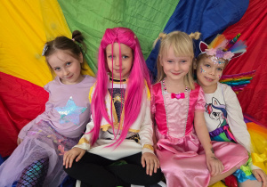 Dziewczynki w strojach karnawałowych siedzą na kolorowej chuście