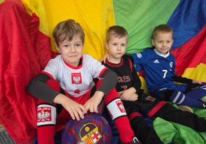 Chłopcy w strojach karnawałowych siedzą na kolorowej chuście