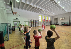 Dzieci trzymają w dłoniach piłki i przygotowują się do rzutu
