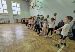 Dzieci trzymają w dłoniach piłki i przygotowują się do rzutu