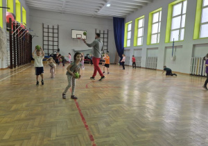 Dzieci biegają po sali i odbijają piłkę
