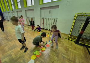 Dzieci układają krążki na lini boiska