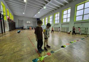 Chłopcy oglądają krążki i znaczniki ułożone na lini boiska