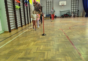 Dzieci biegają dookoła sali gimnastycznej za pachołkami