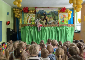 Dzieci siedzą na widowni, oglądają teatrzyk, na scenie słonik pacynka i miś kukiełka