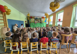 Dzieci siedzą na widowni, oglądają teatrzyk, na scenie słonik pacynka i miś kukiełka i kaczka