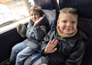 Dwóch chłopców siedzi w autokarze i macha ręką