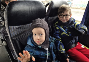 Dwóch chłopców siedzi w autokarze i macha ręką