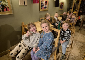 Dzieci siedzą na krzesełkach i czekają na rozpoczęcie przedstawienia