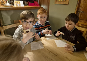 Chłopcy siedzą przy stoliku i jedzą ciasteczka